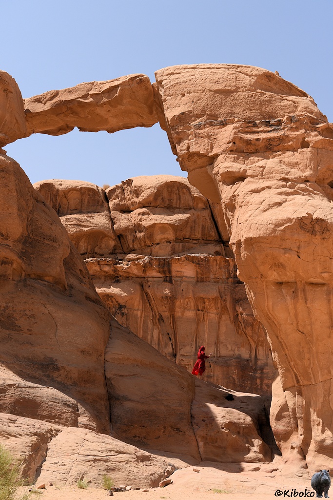 Natürliche Brücke aus Sandstein. Darunter steht eine Dame im Roten Kleid.