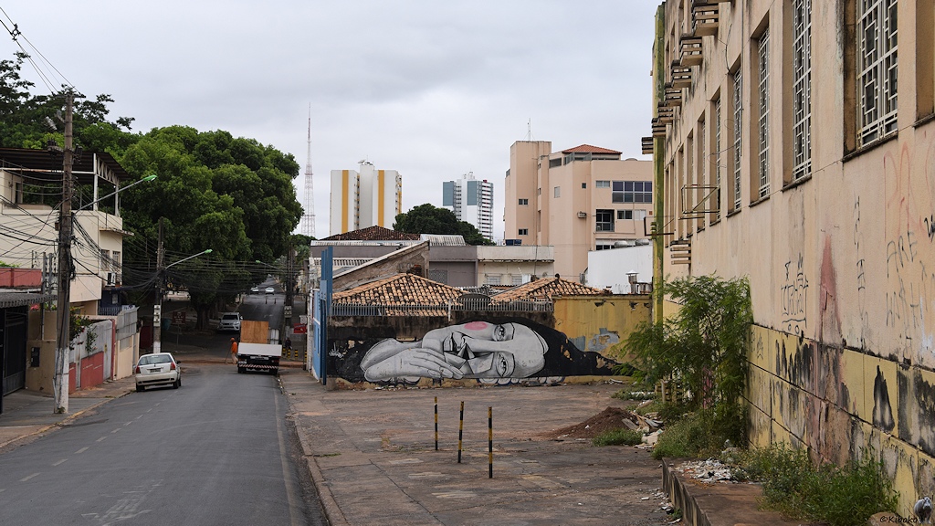 Straße in Cuiabá mit Graffiti an den Häusern, Dreckecken, parkenden Autos und Hochhäuser im Hintergrund