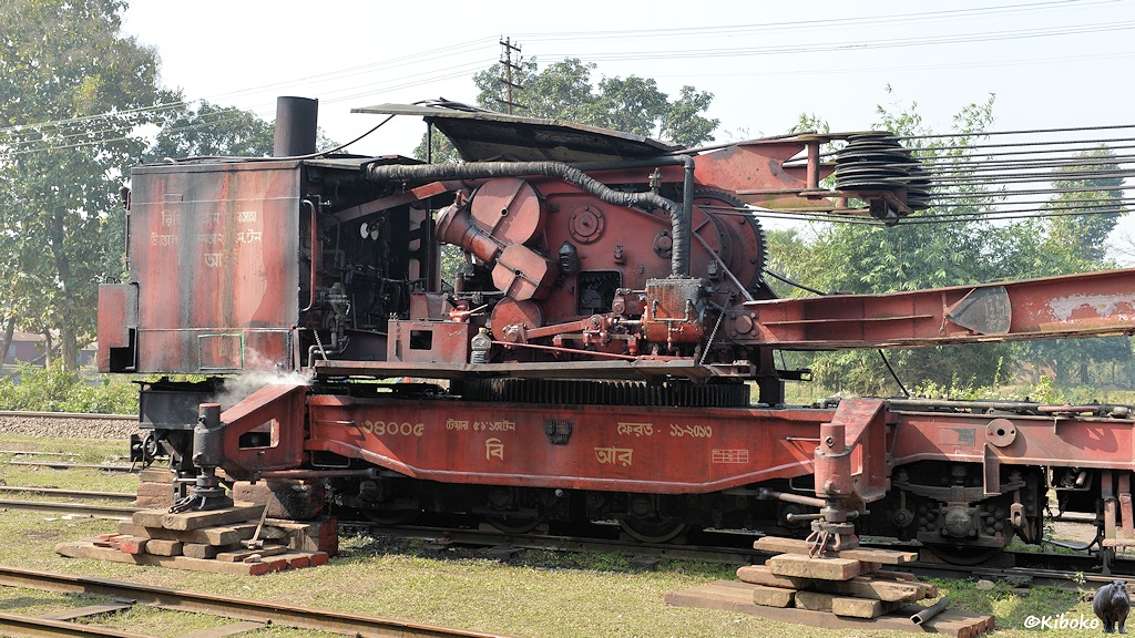 Das Bild zeigt einen roten Dampfkran von der Seite mit Dampfzylinder, Mechanik, und Zahnräder.