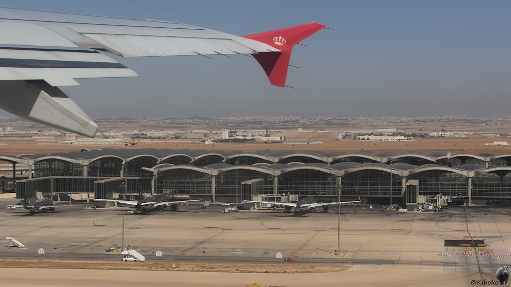 Blick aus dem startenden Flieger auf das Flughafengebäude mit parkenden Flugzeugen