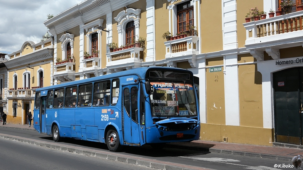 Das Bild zeigt einen blauen Linienbus vor einem braunen Gebäude mit weißen Verzierungen. Die Motorhaube ist hochgeklappt. Der Bus hat die Nummer 2159.