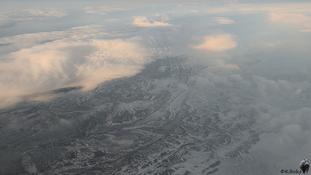 Luftaufnahme auf dunkle Bergformationen mit hellen Schneefeldern