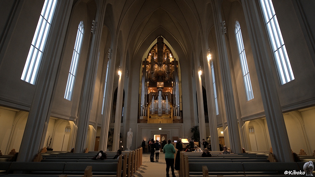 Eine schlichte, weiß gestrichene Kirche von Innen. Über dem Eingang ist eine große Orgel.