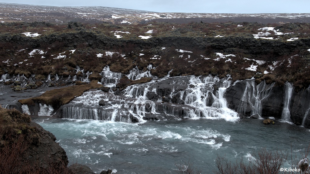 Viele kleine Wasserfälle liegen nebeneinander. Das Wasser fällt über eine oder mehrere Felsstufen in den Fluss.