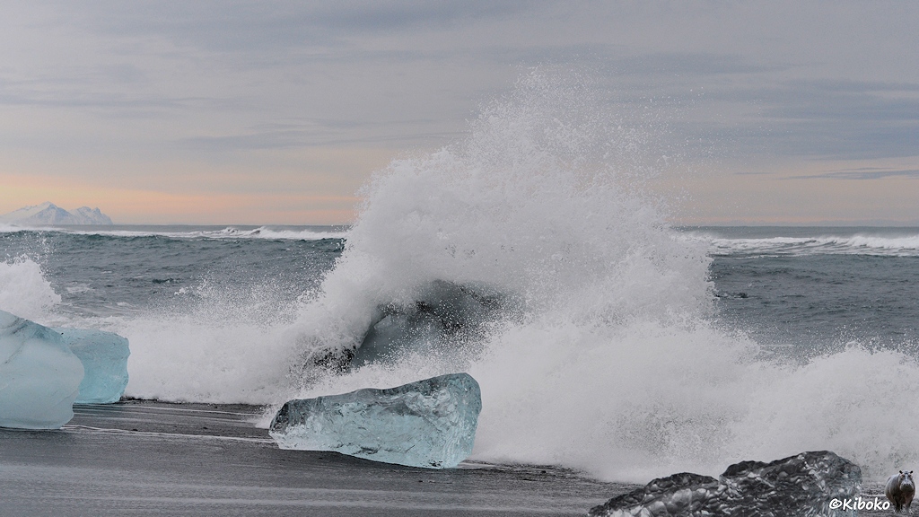 Das Bild zeigt eine größere Welle. Das Wasser trifft auf einen Eisberg und spitzt doppelt so hoch, wie die Welle.