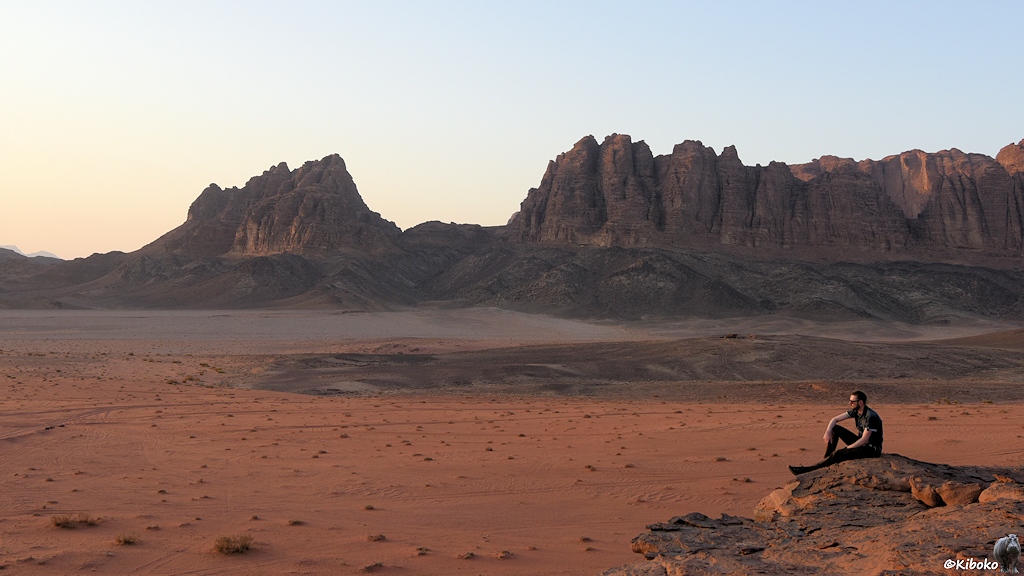 Mann sitzt auf Felsen in der Wüste