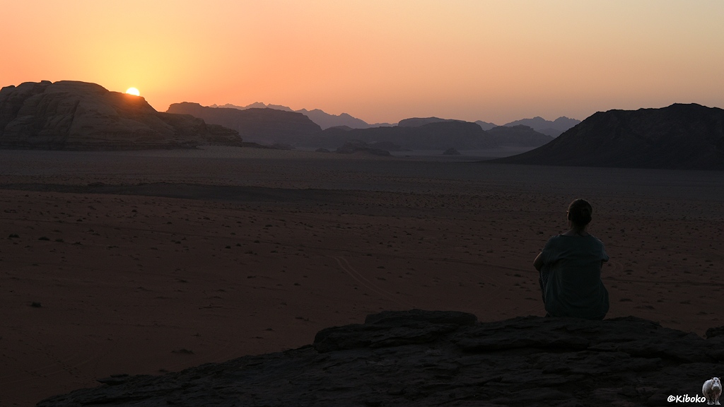 Frau beobachtet untergehnde Sonne in der Wüste