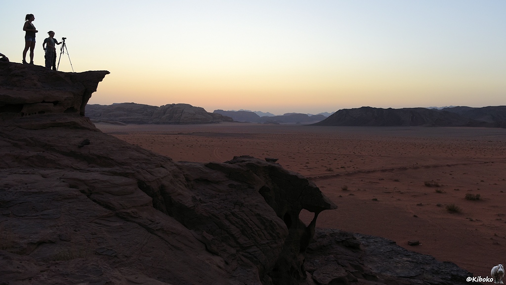 Zwei Fotografinnen stehen auf einen Felsen über der Wüste