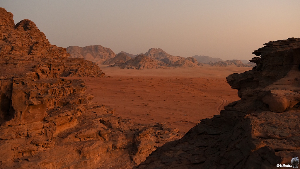 Orangerote Wüste und Sandsteinfelsen im letzten Tageslicht
