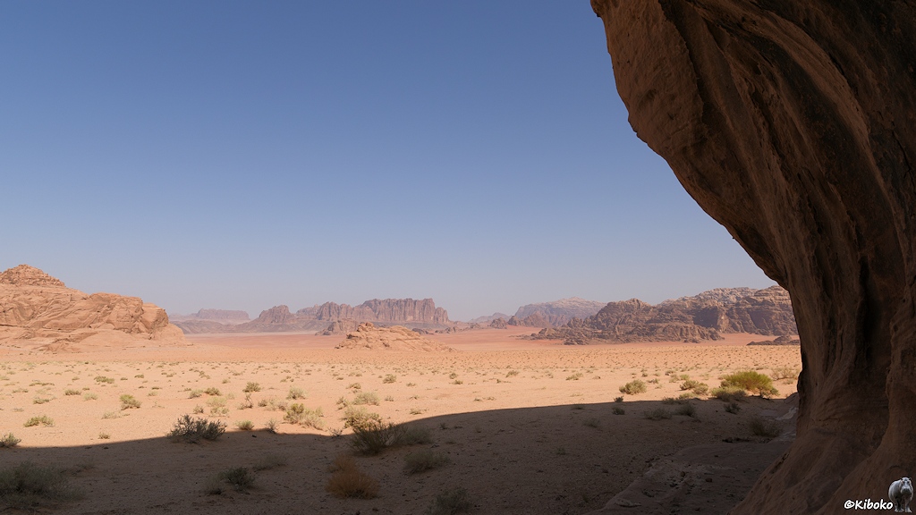 Wüstenlandsaft mit im Schatten liegenden Felsen am rechten Bildrand