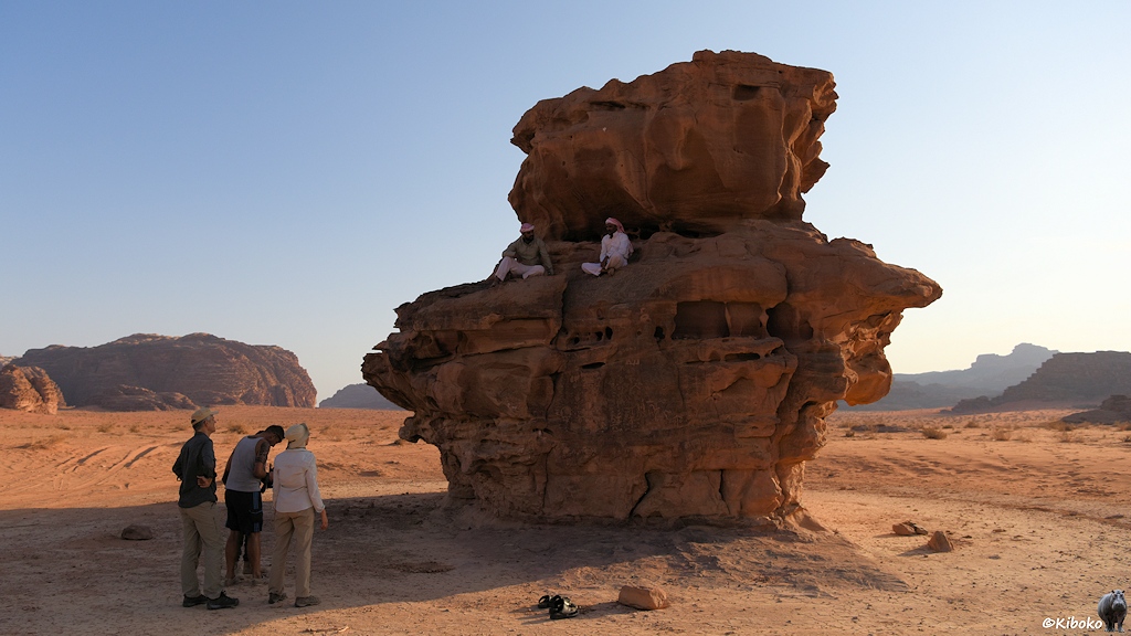 Zwei Beduinen sitzen im Schatten auf einen Felsen