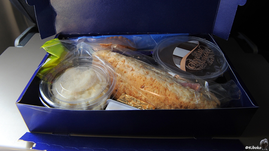 Essen im Flieger, Brötchen, Salat und Nachtisch in blauer Pappschachtel