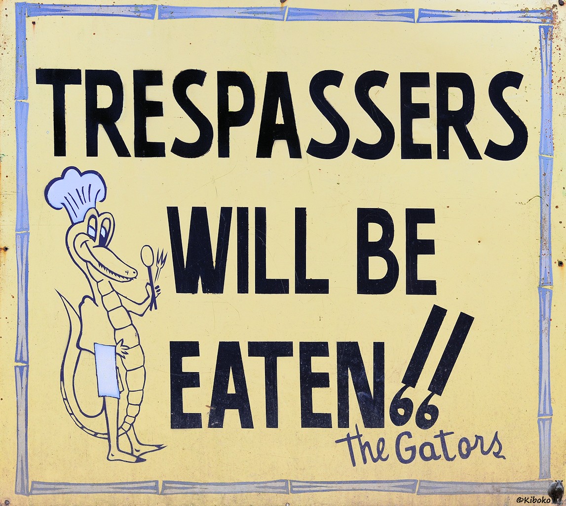 Schild mit einem Krokodil mit Essbesteckt in der Hand und der Aufschrift: Trespassers will be eaten