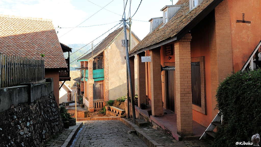 Das Bild zeigt eine gepflasterte Gasse mit gemauerten Awasserkanälen auf beiden Seiten. Ein- und zweistöckige Häuser mit Veranden und Balkonen bereichern das Stadtbild.