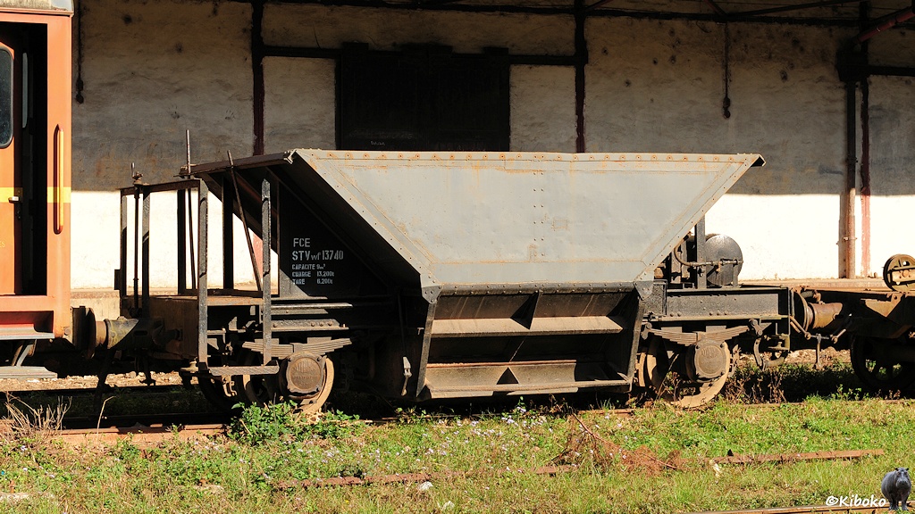 Das Bild zeigt einen zweiachsigen, trichterförmigen, dunkelgrauen Güterwagen mit Entladeöffnungen in Bodennähe.