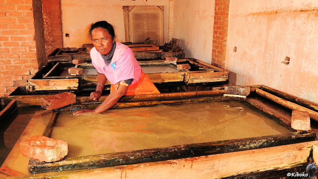 Das Bild zeigt eine Frau, die den beigefarbenen Faserbrei in einem Holzrahmen verteilt.