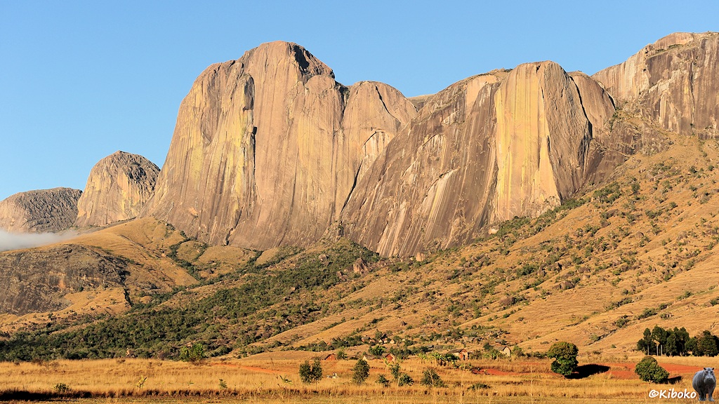 Das Bild zeigt eine Berg mit hohen, senkrechten Felswänden. Darunte rist ein Ort aus vereinzelten kleinen Häusern.