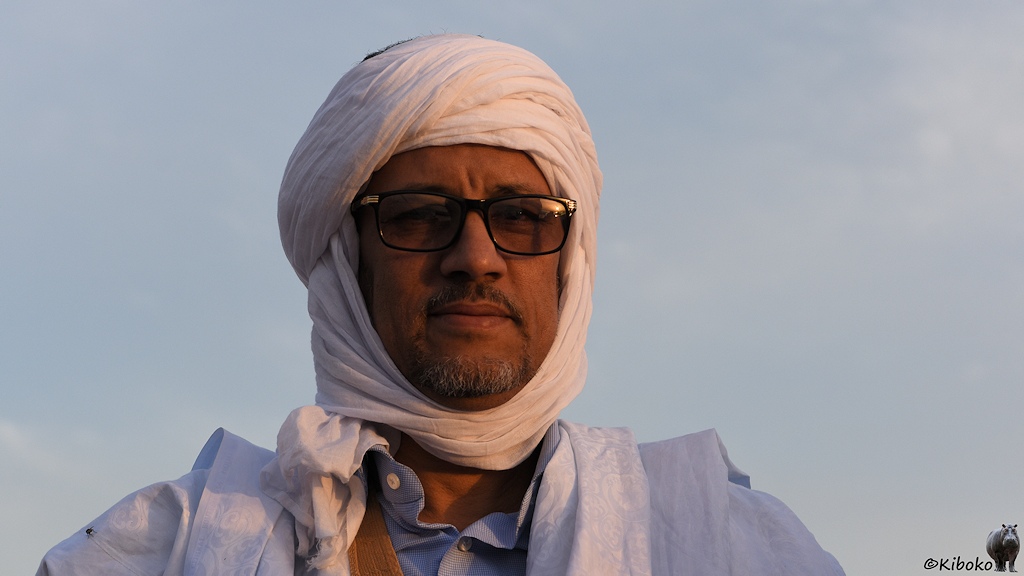 Das Bild zeigt das Porträt eines Mannel mit dunkler Sonnenbrille, weißen Turban und hellblauem Gewand.