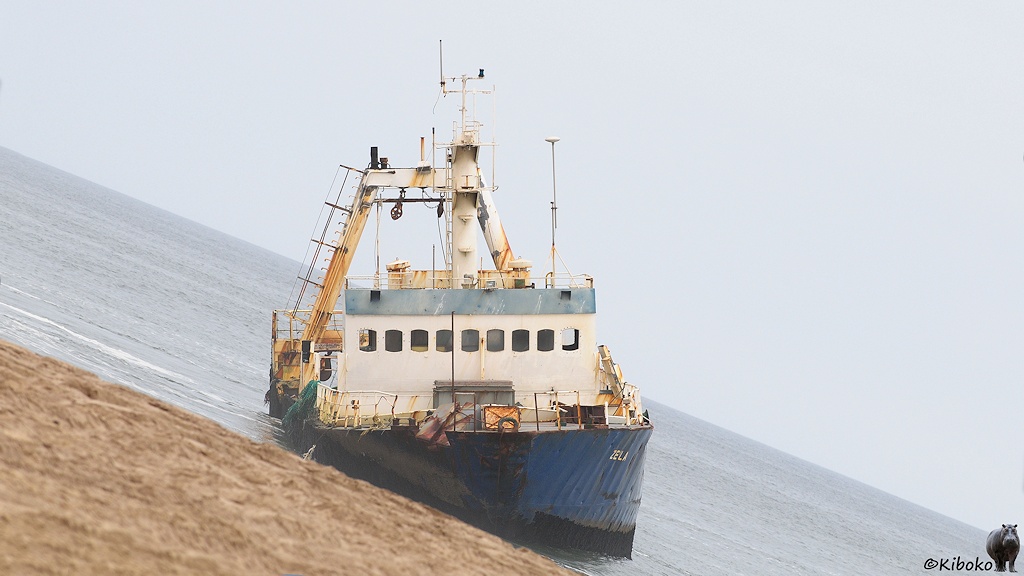 Das Schiff liegt schräg am Strand. Auf dem Bild ist das Schiff gerade und der Horizont verläuft diagonal.