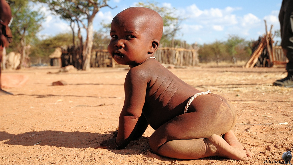 Ein Baby krabbelt über den Dorfplatzes.