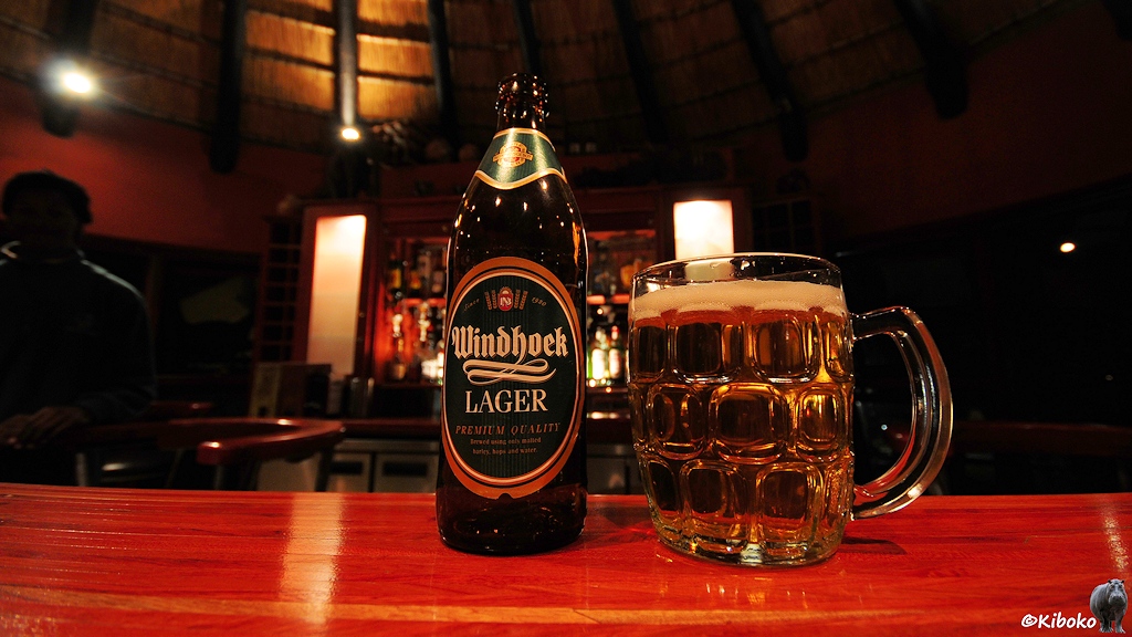 Ein Windhoek Lager Bierflasche und ein volles Bierglas stehen auf dem Tresen.