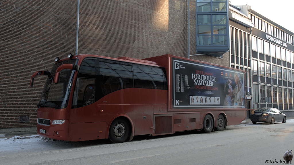 Das Bild zeigt eine Mischung aus Reisebus und LKW. Im ersten Drittel sind Sitzreihen. Dahiner kommt ein geschlossener Aufbau in der Größe eines Containers. Der Bus ist dunkelrot lackiert und hat eine Werbeaufschrift am Aufbau.