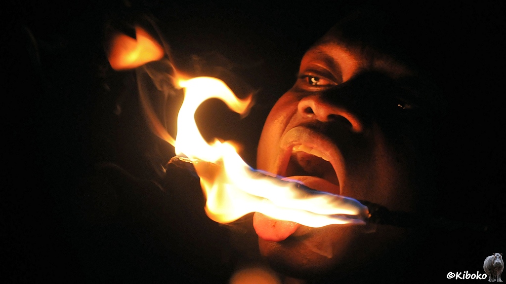 Ein Mann hält seine Zunge an die brennende Fackel.